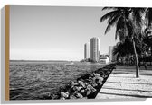 Hout - Palmbomen op het Strand met Uitzicht op Hoge Gebouwen Zwart/Wit - 60x40 cm - 9 mm dik - Foto op Hout (Met Ophangsysteem)