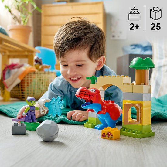 Een jongetje speelt met LEGO Duplo blokken, waaronder een rode en blauwe dinosaurus, groene goblin en een fort.