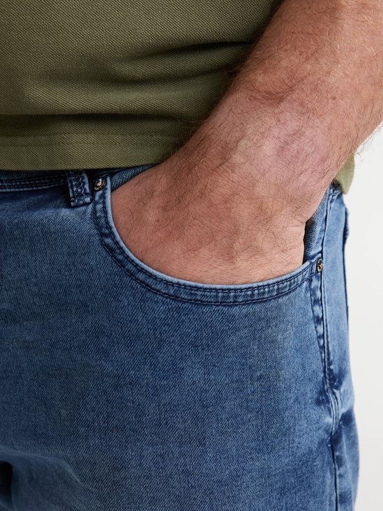 Close-up van de rechterzak van een blauwe denim short. Een hand van een man is in de zak gestoken.