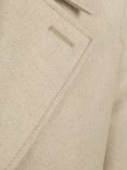 Detail van crèmekleurige wollen jas met linnen stof, stiksels en knoopsgat.