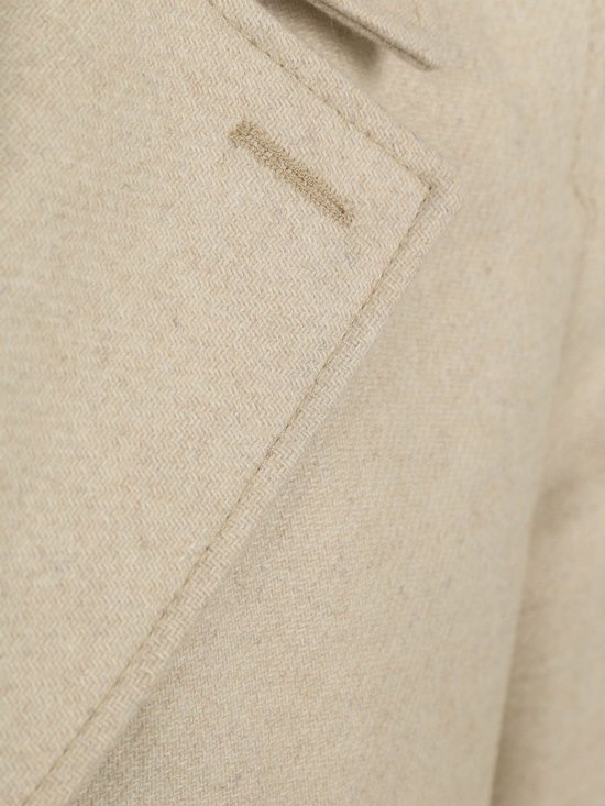 Detail van crèmekleurige wollen jas met linnen stof, stiksels en knoopsgat.