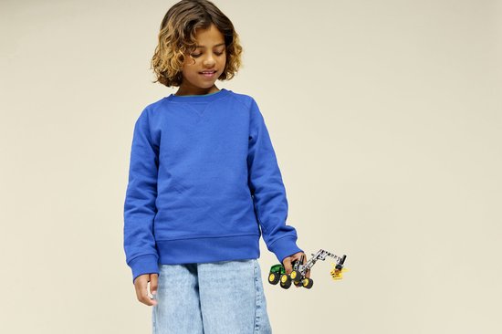 Jongen in blauwe trui met LEGO Technic John Deere 1470H bosbouwmachine in zijn hand.