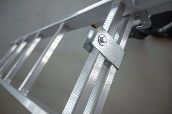 Detail van een metalen beugel met een bout en moer die twee ronde aluminium ladderbuizen verbindt.