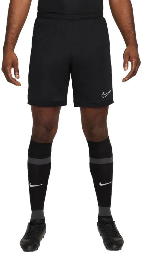 Man in zwarte Nike shorts met witte swoosh op linker broekspijp en grijze sokken.