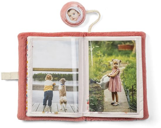 Zacht roze stoffen fotoalbum met twee foto's: kind met hond bij water en meisje met gieter. Speelgoedje met babygezichtje.