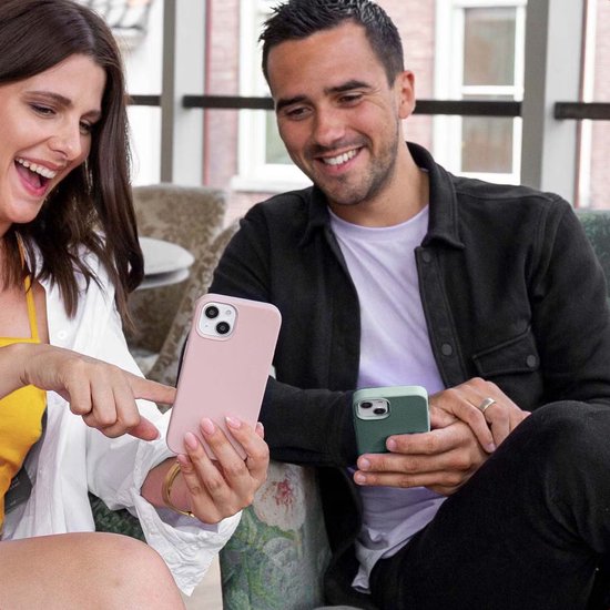 Vrouw en man met roze en groene telefoonhoesjes, kijkend naar een telefoon.