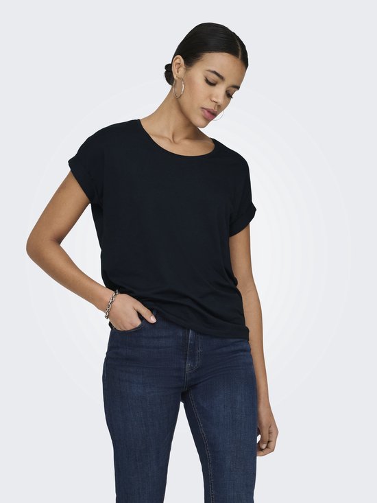 Model in zwart T-shirt met opgerolde mouwen en donkere jeans.