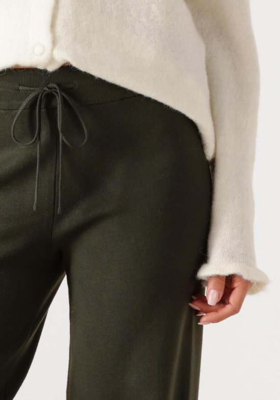 Dames met donkergroene broek met trekkoord en witte gebreide cardigan.