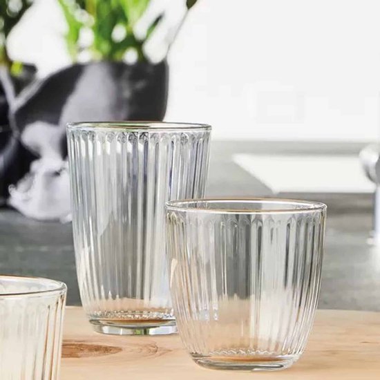 Deux verres longdrink nervurés verticalement sur une planche en bois.