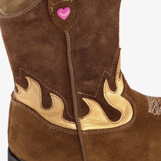 Close-up van bruine suède cowboylaars met goudkleurige vlammenapplicatie en roze hartje.