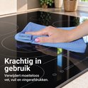 Een hand met een blauwe microvezeldoek van 'Clean Dry' die een glazen kookplaat schoonmaakt.