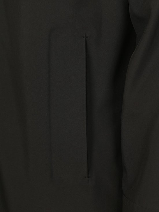 Detail van een zwarte jas met een verticale naad en een ingewerkte zak.