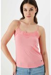 Model draagt een roze kanten top met spaghettibandjes en een spijkerbroek