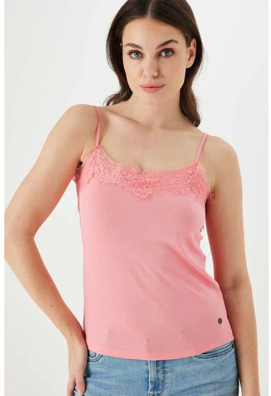 Model draagt een roze kanten top met spaghettibandjes en een spijkerbroek