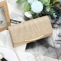 Gouden glitter clutch met gouden gesp en ketting, gefotografeerd met bloemen.