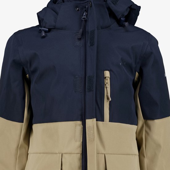 Detailopname van een donkerblauwe en beige outdoorjas met rits en klittenbandsluiting.