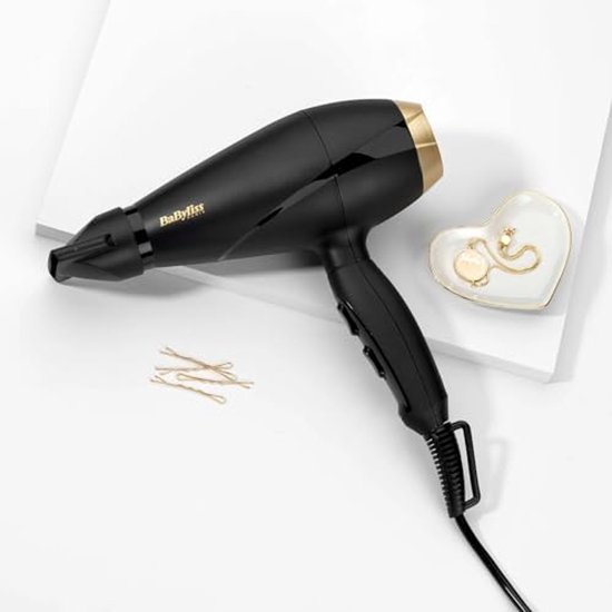 Zwarte BaByliss föhn met gouden details, concentrator, haarspeldjes en sieraden op een witte ondergrond.