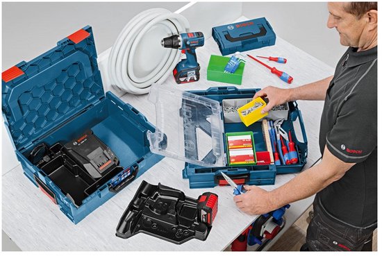 Man vult blauwe Bosch L-BOXX gereedschapskoffers met een accuboormachine, lader en diverse handgereedschappen.