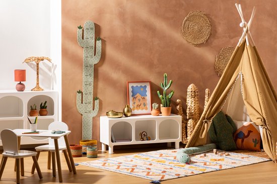 Kinderspeelkamer met een witte tafel en stoelen, een beige tipi, een cactusoordop en een zandkleurige muur.