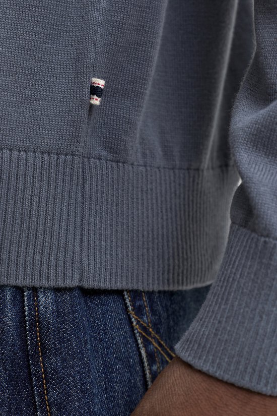 Donkerblauwe gebreide polo met subtiele rode en witte details op een mannelijk model.