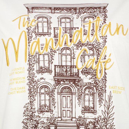 Geborduurd Manhattan Café-ontwerp op een wit T-shirt.