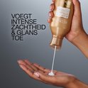 Mains d'une personne tenant une bouteille Redken 'All Soft', tandis que la crème est dispensée dans la main. Texte : 'AJOUTE DOUCEUR INTENSE &amp; BRILLANCE'.