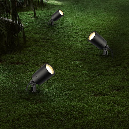Drie zwarte Ledvion grondspots verlichten een grasveld 's nachts.