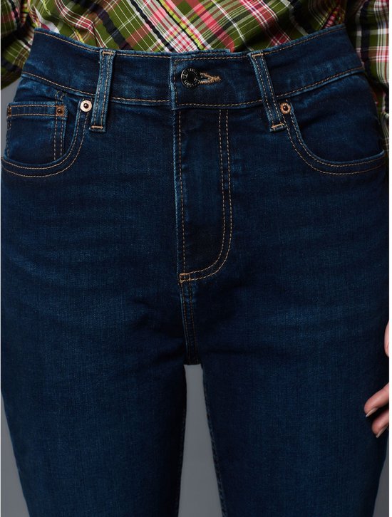 Bovenkant van een donkerblauwe jeans met ritssluiting, gedragen door een model.