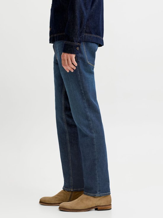 Detail van een medium blauwe jeans en suède laarzen, gedragen met een donkerblauw denimjack.