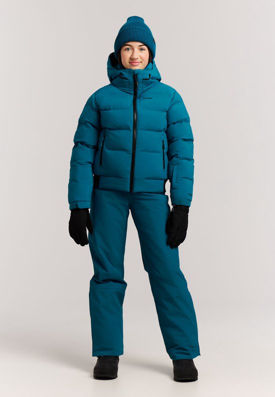 Meisje in blauwe ski-jas, muts, broek en handschoenen. Zwarte rits en zwarte streep op de mouw.