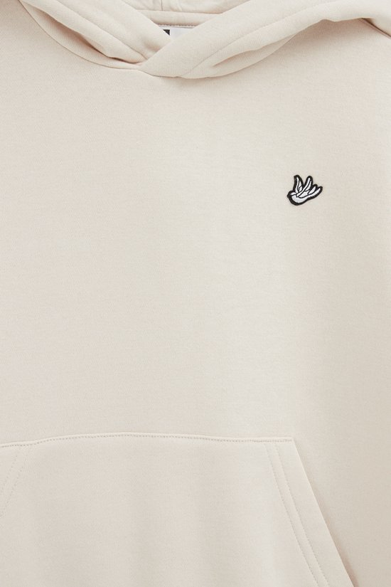 Detail van beige hoodie met geborduurd handlogo op de borst en buidelzak.