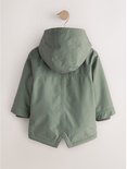 Achterzijde van een groene parka met capuchon, hangend aan een kleerhanger tegen een lichte achtergrond.