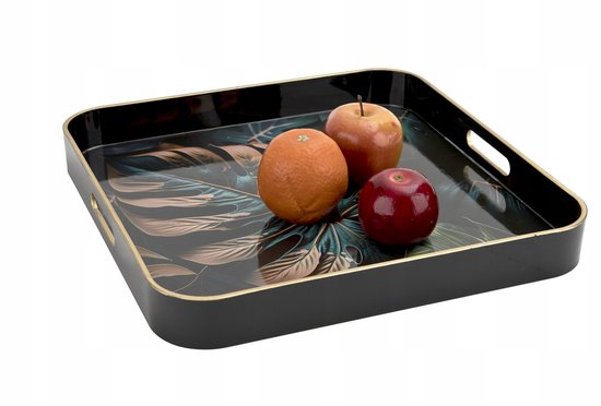 Zwart dienblad met gouden rand, bedrukt met bladeren, met een sinaasappel en twee appels erop.