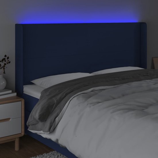 Tête de lit bleue en tissu avec un subtil éclairage LED bleu au-dessus du lit, avec couette.
