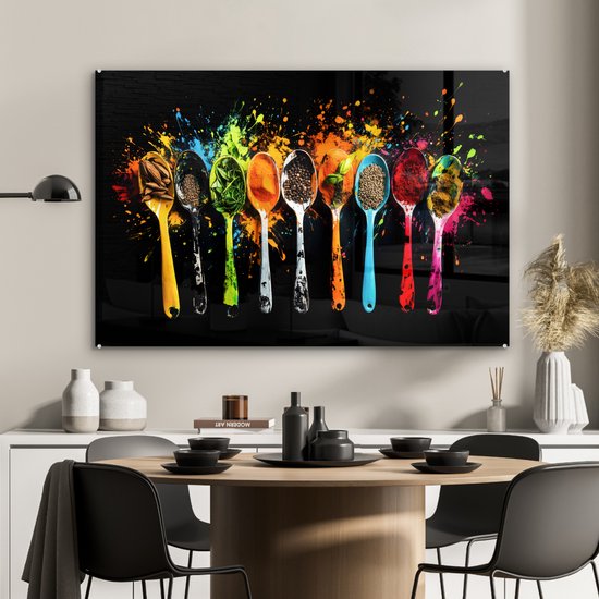 Un panneau mural en verre avec des cuillères colorées pleines d'épices et d'herbes, et des éclaboussures de peinture, au-dessus d'une table à manger.