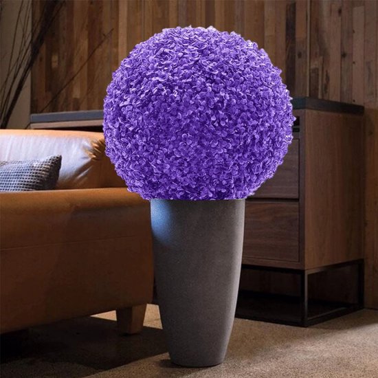 Paarse sierbal van kunstplantjes in een grote grijze pot, in een woonkamer.