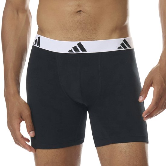Man draagt een zwarte boxer met witte band en zwarte Adidas logo's.