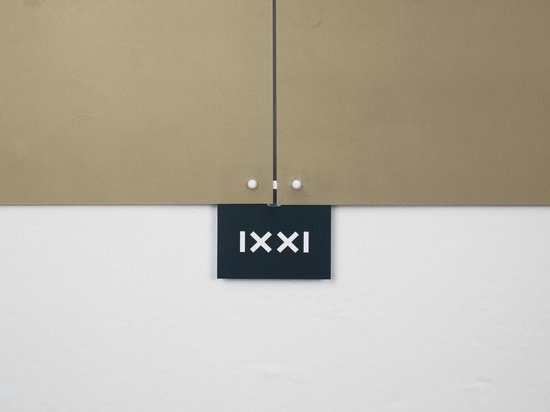 Une étiquette détachable avec 'IXXI' en lettres blanches sur un fond noir, fixée à la décoration murale.