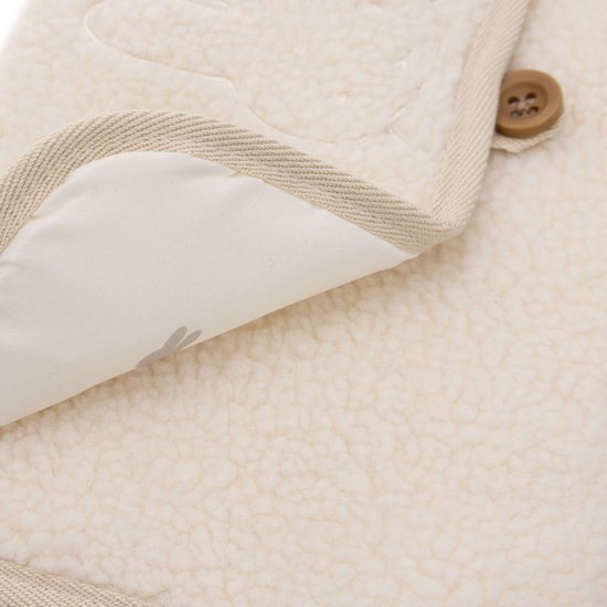 Close-up van een crèmekleurige teddy verschoonmat met beige rand en een houten knoopje. De binnenkant toont een Nijntje print.