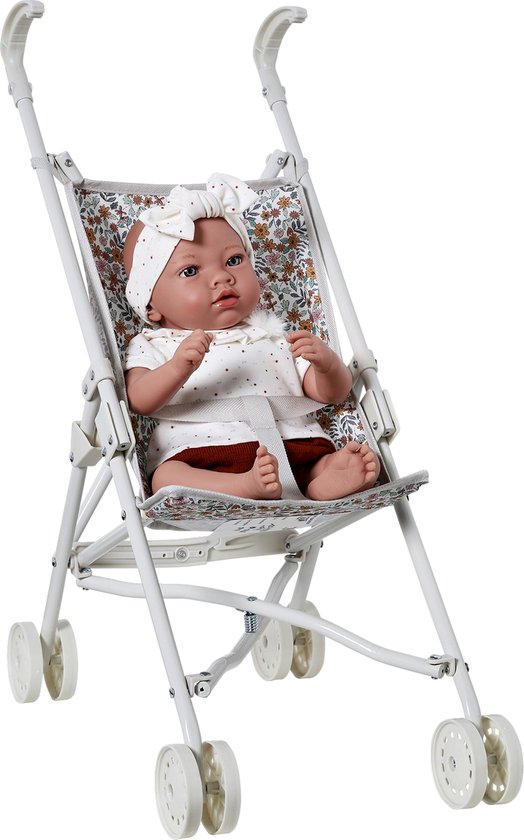 Pop met witte top en bruine broek, zittend in een witte kinderwagen met bloemenprint.