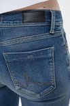Details van de achterkant van een blauwe spijkerbroek met zwarte leren patch.
