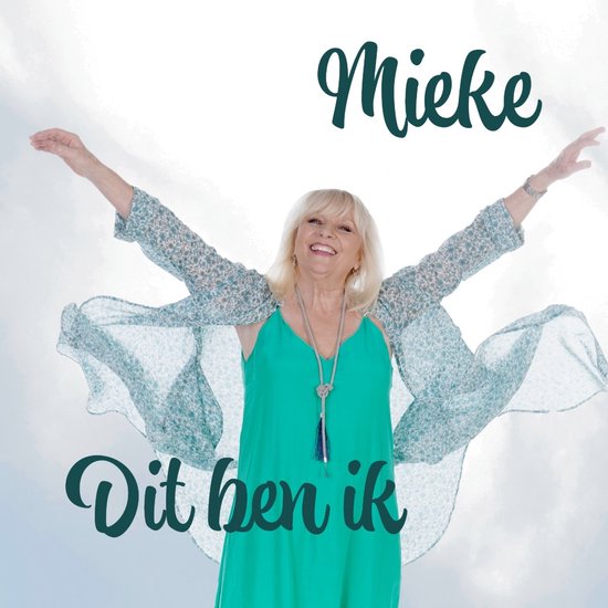 Vrolijke vrouw met open armen, draagt een turquoise jurk en een vest met blauwe bloemenprint. Titel: Mieke - Dit Ben Ik