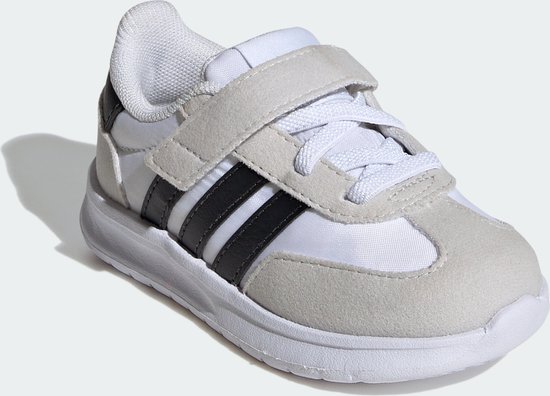 Witte kindersneaker met grijze suède overlays, zwarte Adidas-strepen en klittenbandsluiting.
