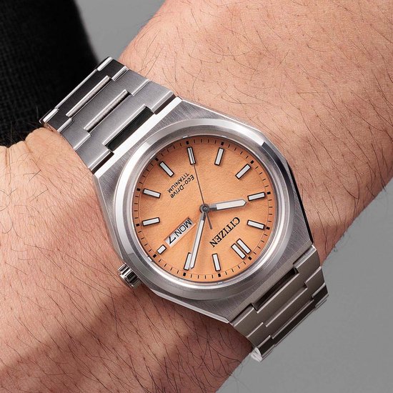 Citizen Eco-Drive horloge van zilverkleurig titanium met perzikkleurige wijzerplaat op een mannelijke pols.
