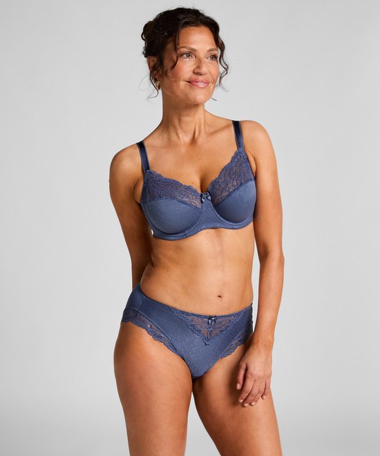 Model draagt een blauwe bh met stippenpatroon en kanten details, met bijpassende slip.