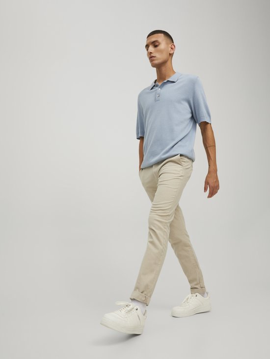 Man lopend in lichtblauwe polo en beige chino.