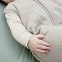 Detail van babyhandje op een beige babyslaapzak.