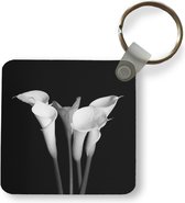Sleutelhanger - Een close up van calla lily-bloemen op een zwarte achtergrond - Plastic - Rond - Uitdeelcadeautjes