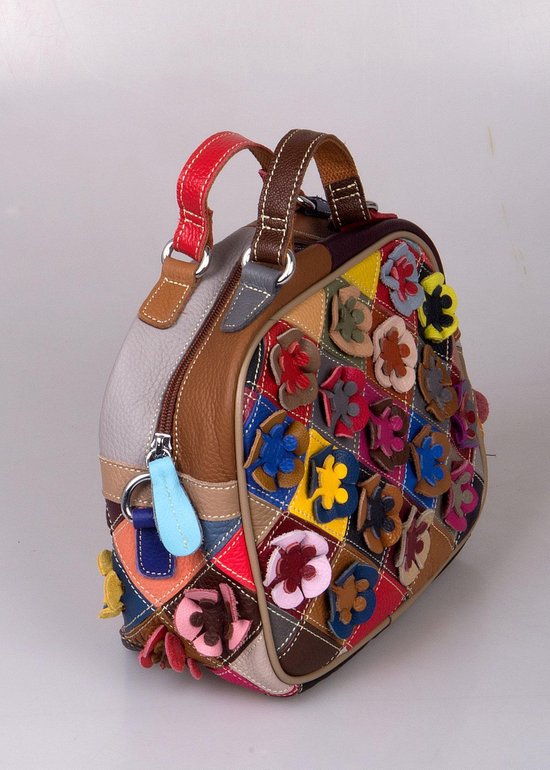 Zijaanzicht van een veelkleurige patchwork tas met bloemapplicaties en leren hengsels.