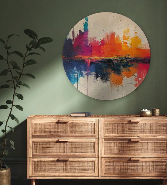 Abstracte muurcirkel met felle kleuren op een groene muur boven een houten dressoir.